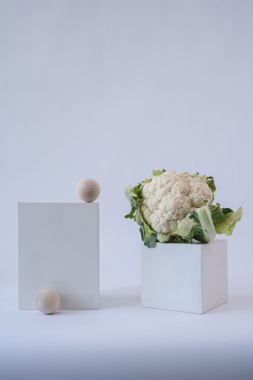 Free Artistic still life featuring cauliflower on white cubes in a studio setting. Stock Photo