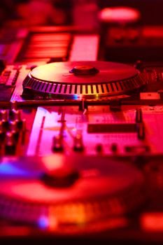 Close-up of a DJ turntable with colorful lighting in a music studio environment.
