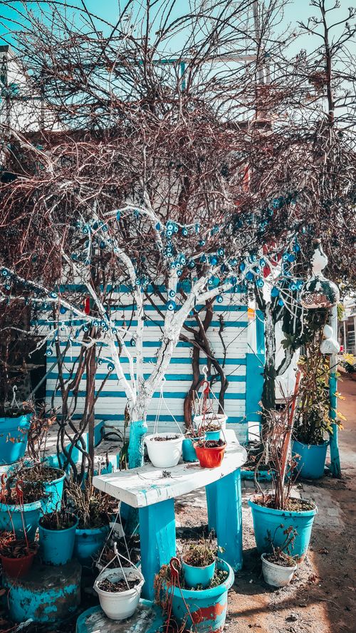 Free A quaint garden in Gümüşlük, Türkiye featuring potted plants and traditional evil eye decorations. Stock Photo