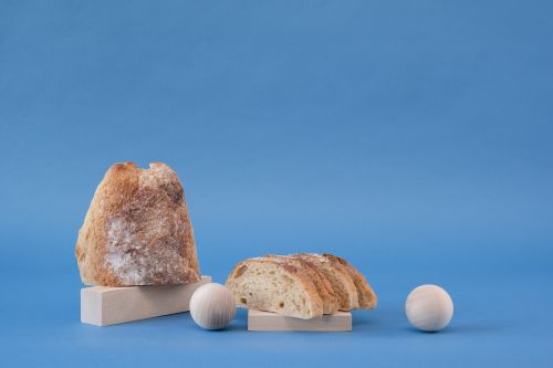 Free Creative studio photo of ciabatta bread with wooden elements against a blue backdrop. Stock Photo