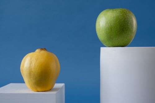 Free Close-up of yellow and green apples on geometric white pedestals against a blue background. Stock Photo