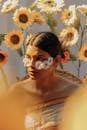 Female with flowers on face standing among blooming sunflowers in sunlight