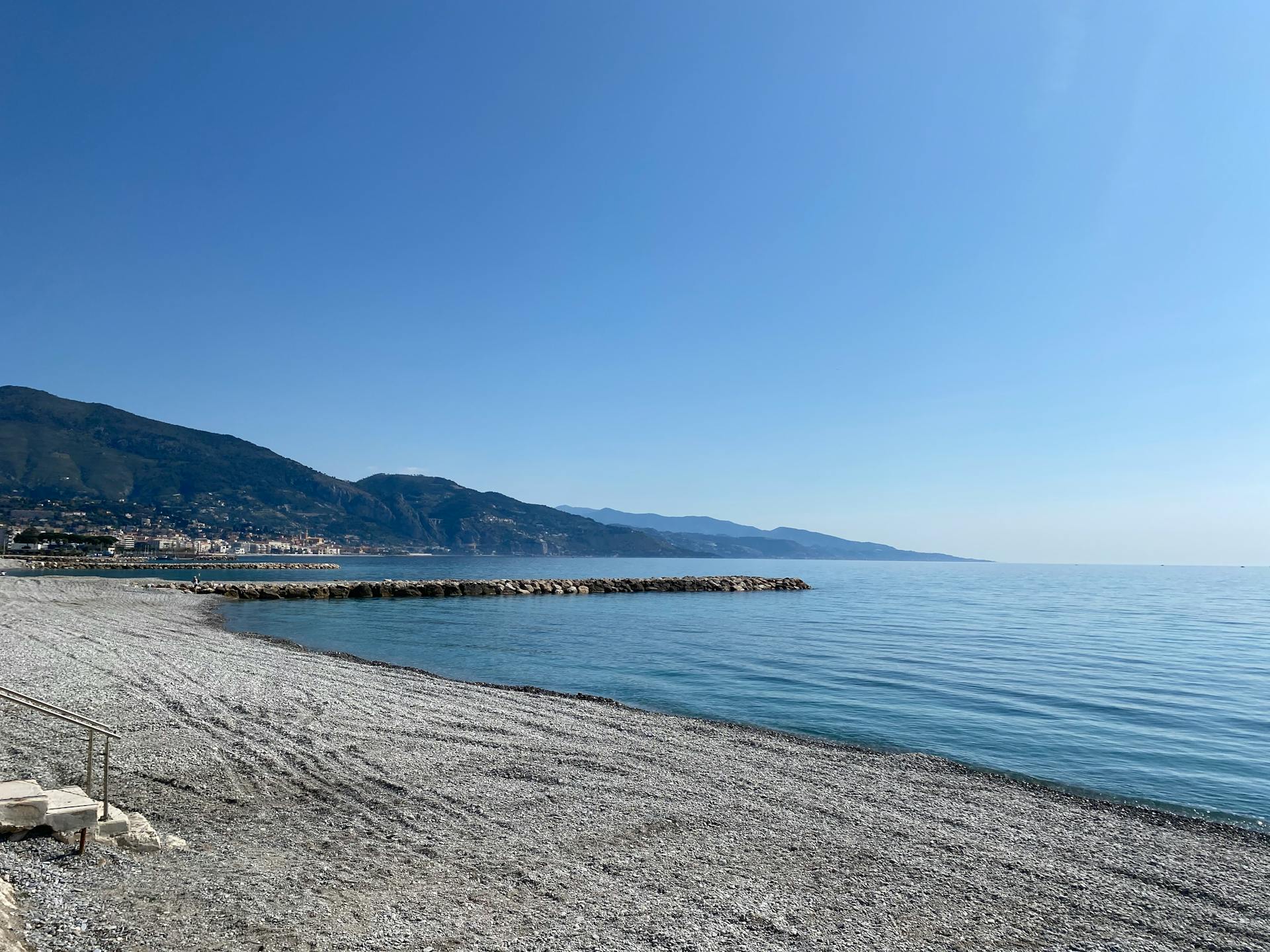 Rocky Seashore Near Mountain Under Blue Sky