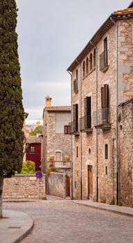 Rustic stone buildings and cobblestone street in historic Gerona, showcasing classic architecture.
