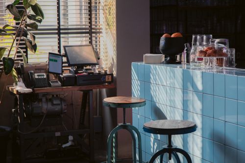 Free Warm and inviting office space with cafe bar counter, stools, and natural lighting. Stock Photo