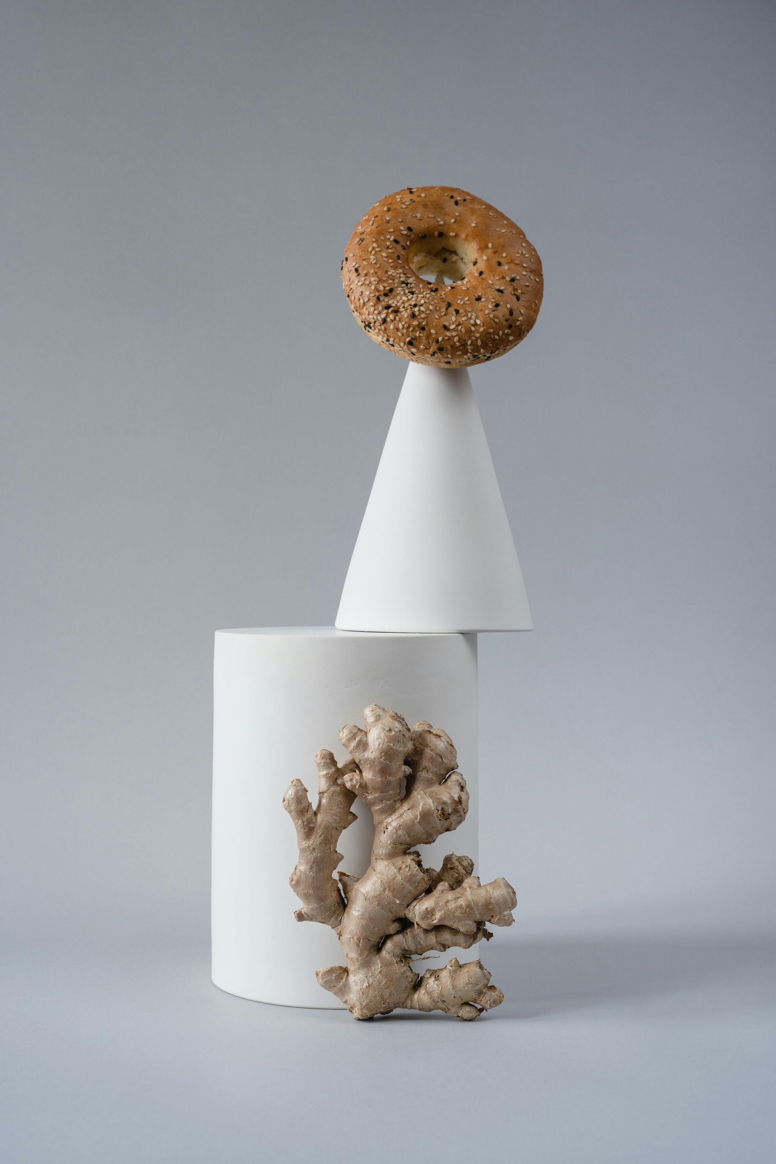Artistic display of a bagel and ginger on geometric shapes, minimalist style.