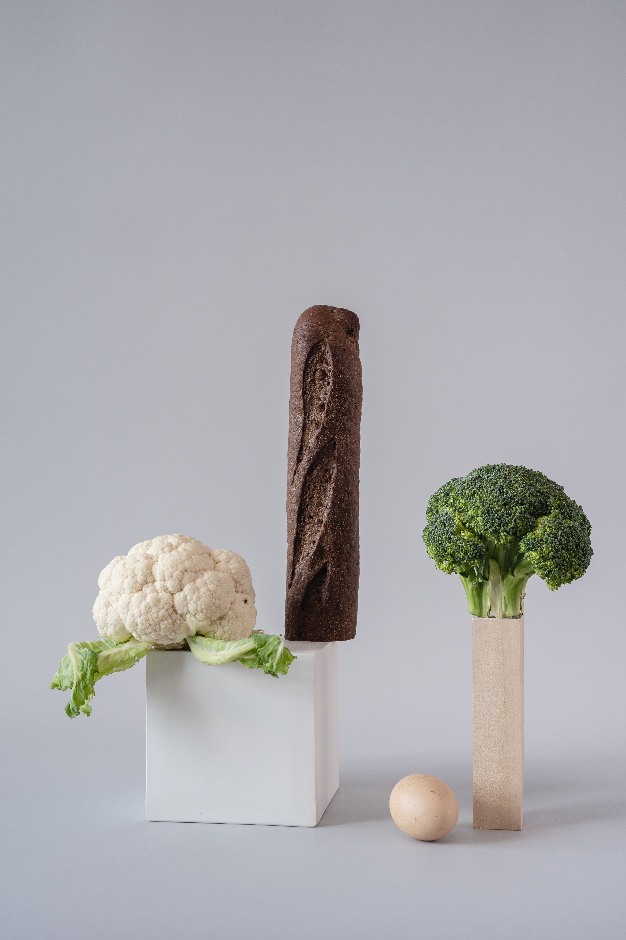 Artistic arrangement of bread and vegetables on a gray background.