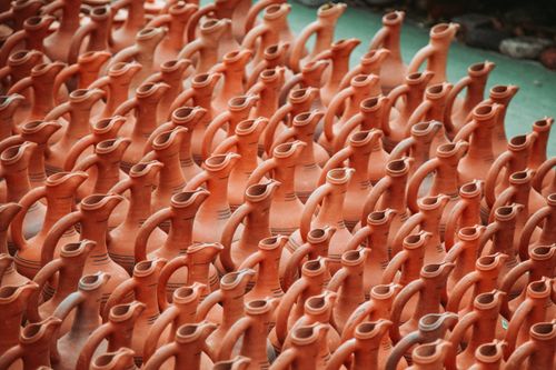 Free Rows of handcrafted orange clay pottery with handles and spouts in artistic repetition. Stock Photo