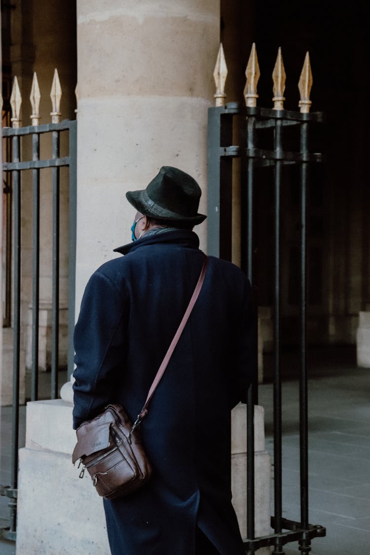 A Man In Blue Coat Walking On The Street