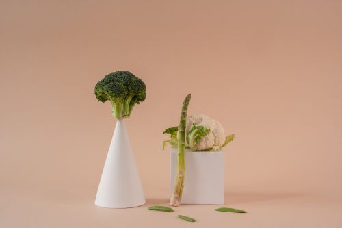 Free Conceptual display of broccoli, cauliflower, and asparagus on pastel beige background. Stock Photo