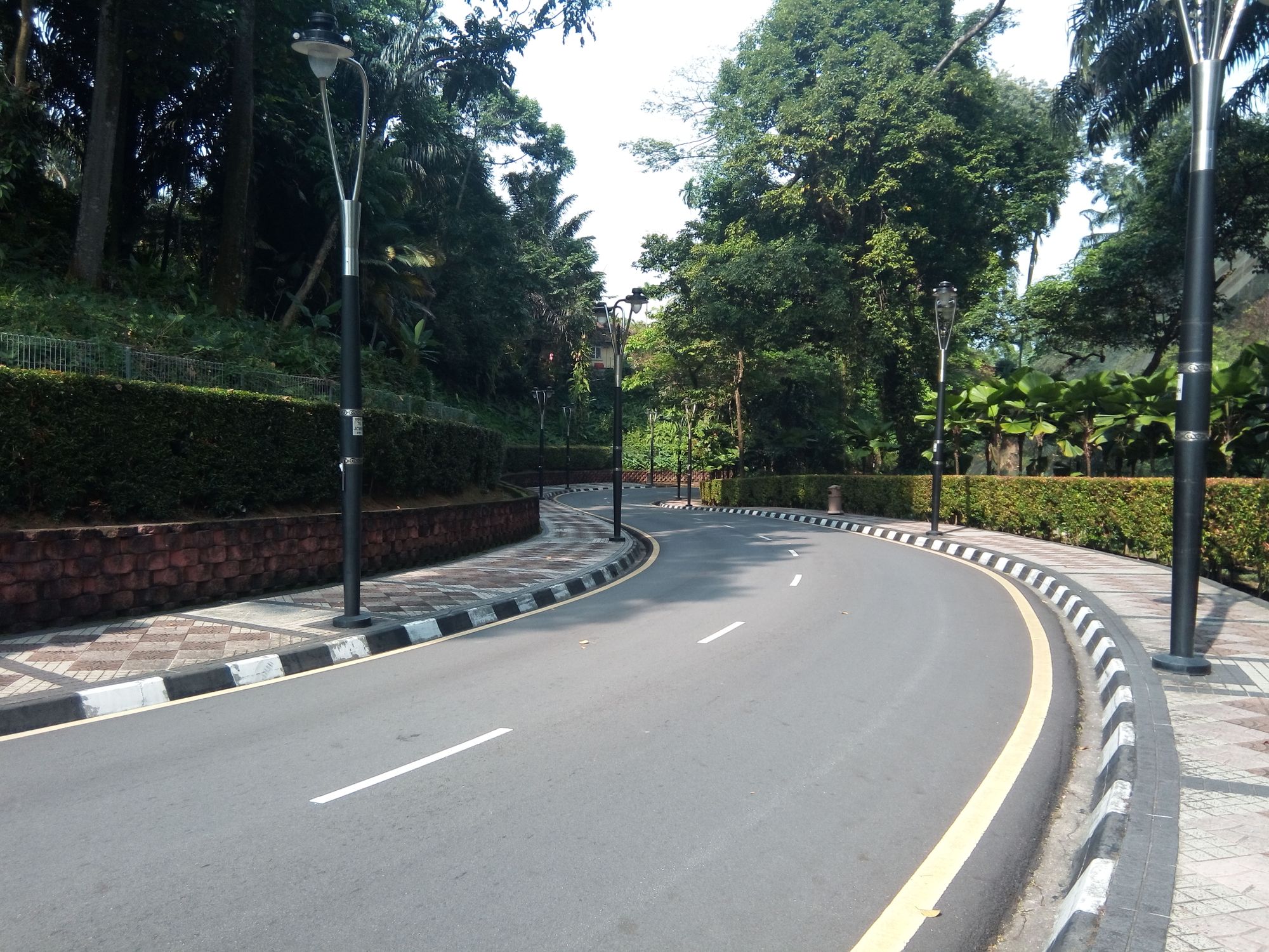 A scenic curved road lined with street lamps and greenery in Kuala Lumpur, Malaysia