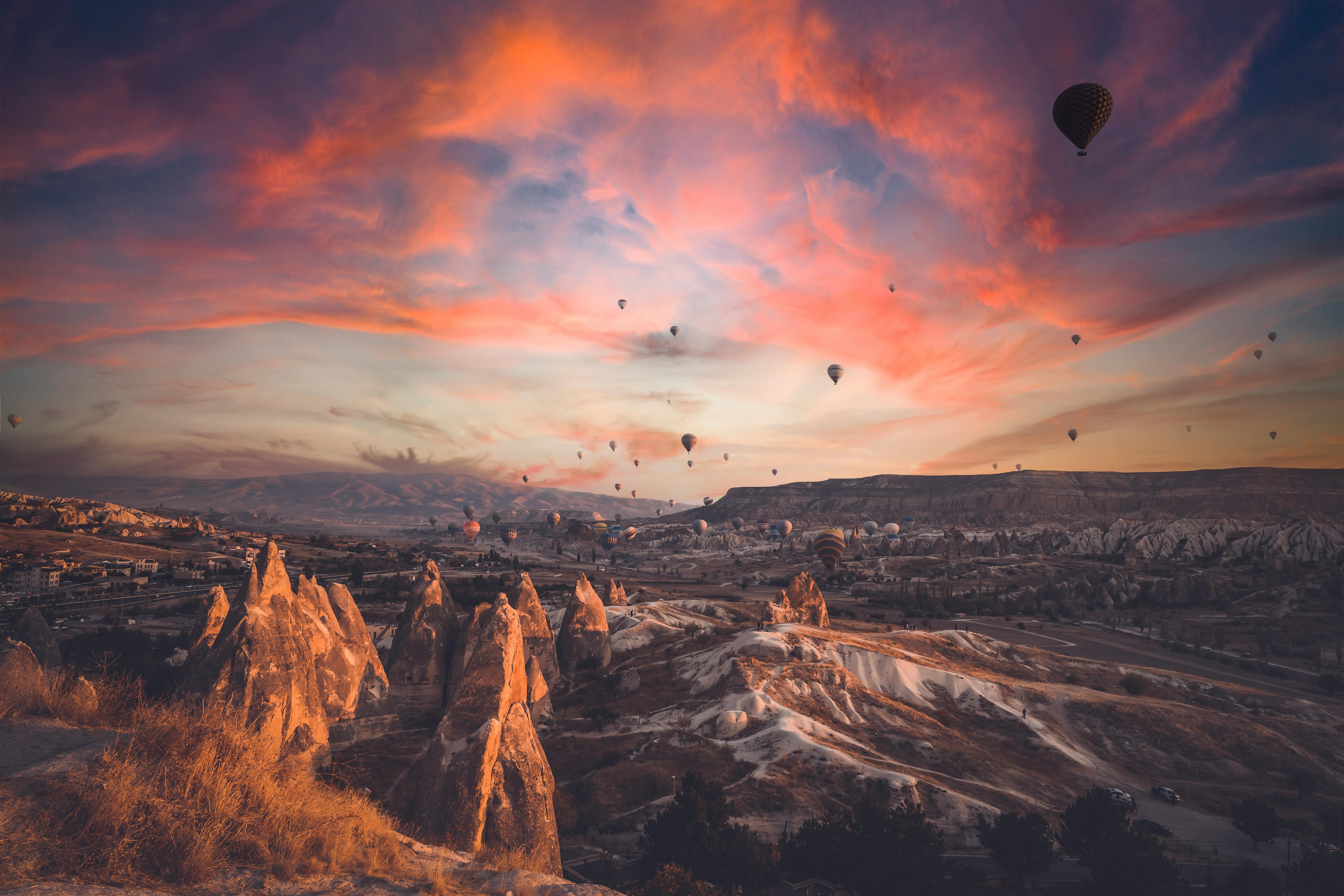 Stunning sunset view of hot air balloons over Cappadocia's unique landscape.