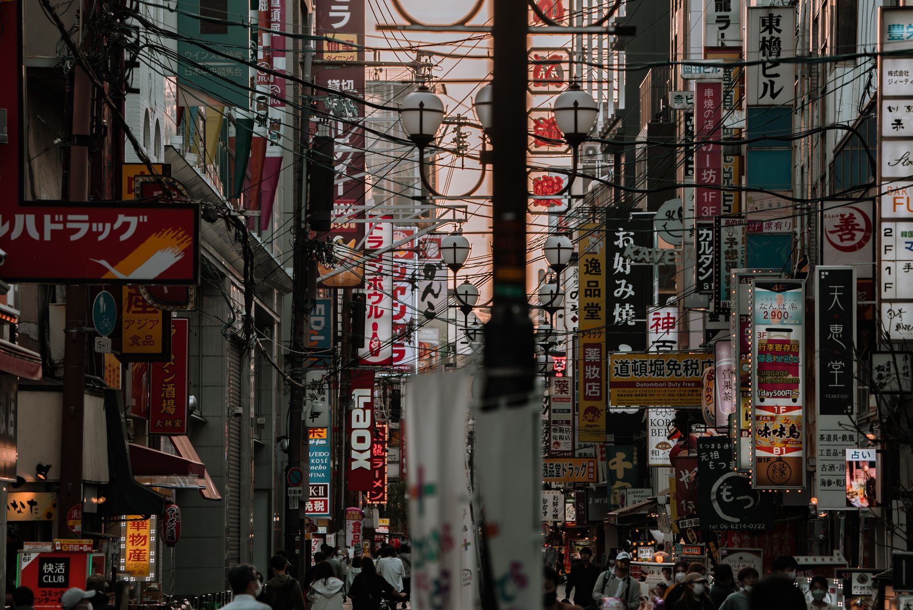 Explore the vibrant urban landscape of Osaka with bustling streets filled with colorful signages.