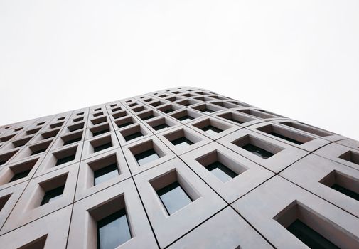 Dynamic low-angle shot of a modern building facade in Nanjing, highlighting geometric patterns and glass windows.