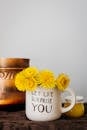 Yellow dandelions placed in light mug against wall