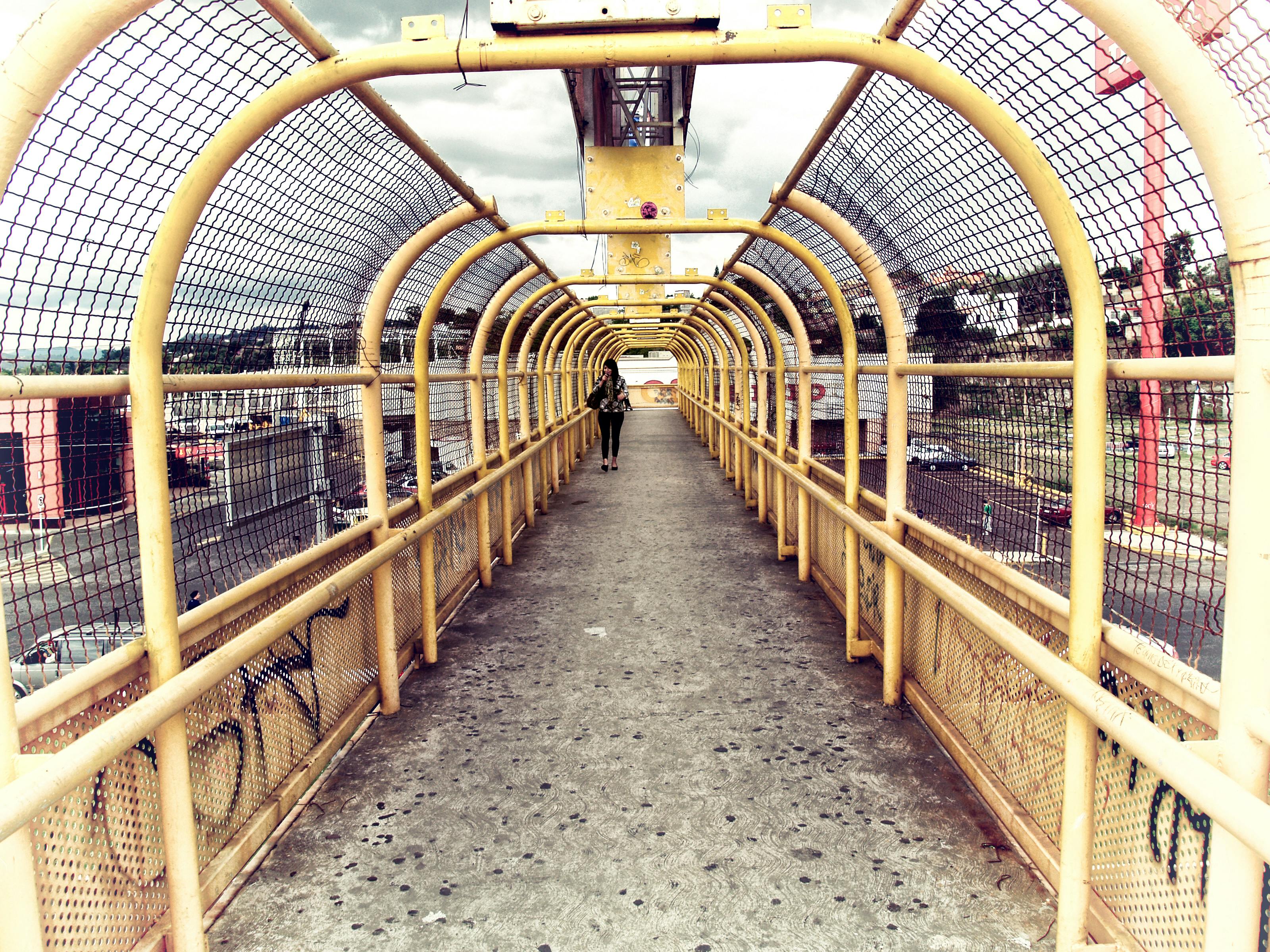 一座现代化的人行桥采用黄色铁丝网和独行者设计，创造出引人注目的城市景观