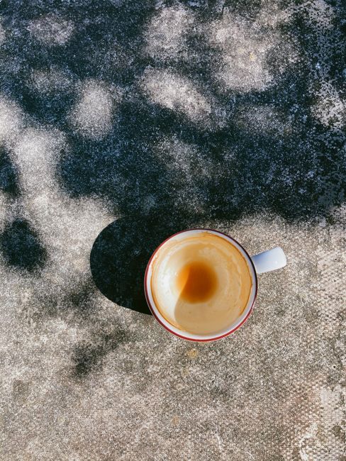 Top view of cup of drunk hot coffee placed on table on sunny day on terrace