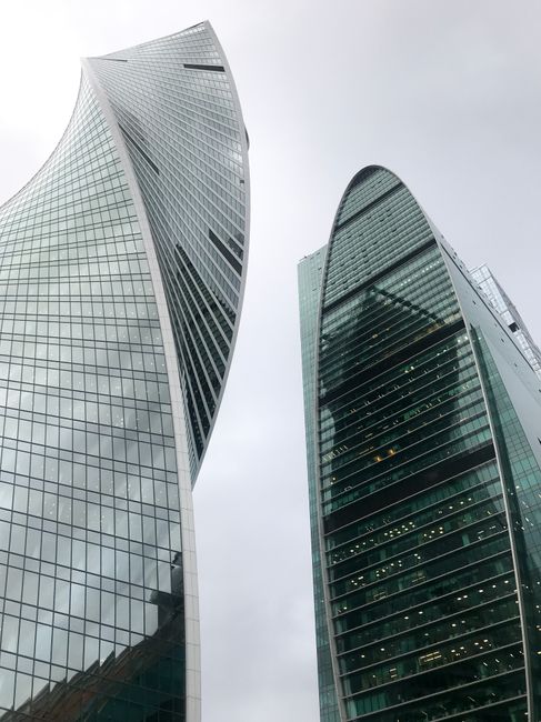 Elegant city skyscrapers with glass facades showcasing modern architectural design under a cloudy sky.