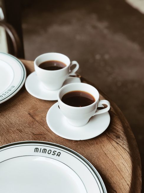 Two cups of black coffee on a wooden table, perfect for a cozy café atmosphere.