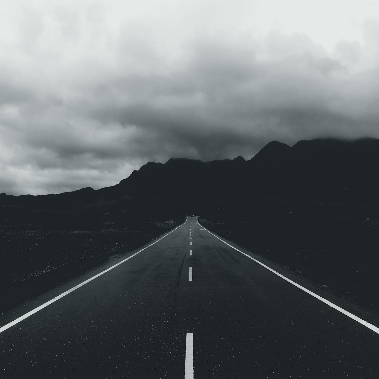 Grayscale Photo of a Road Heading to Mountain · Free Stock Photo