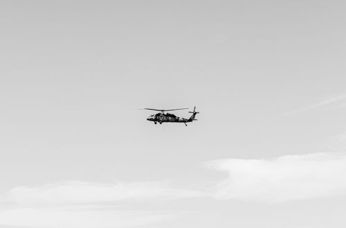 Free A black and white photo of a helicopter flying through a bright sky, showcasing aviation in motion. Stock Photo