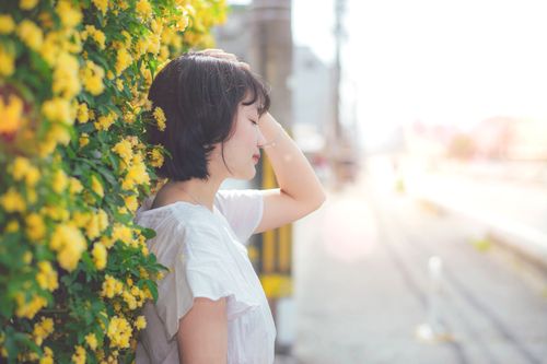 Free A serene woman enjoying a peaceful moment by a vibrant yellow flowering hedge outdoors. Stock Photo