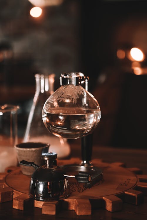 Water in glass sphere of siphon coffee maker with heater placed on table in cafe