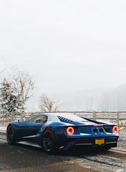 A striking blue Ford GT supercar parked on a snowy road, showcasing its sleek design and winter setting.