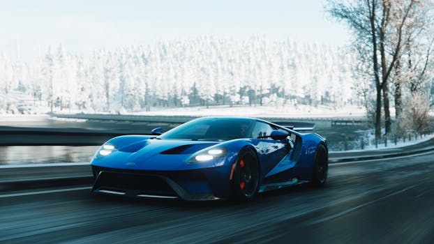 A luxurious blue sports car speeds through a snowy landscape, showcasing elegance and performance.