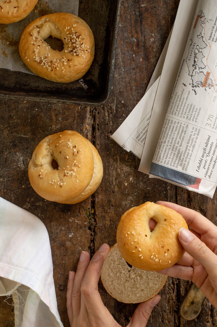 A Person Holding A Sliced Bagel