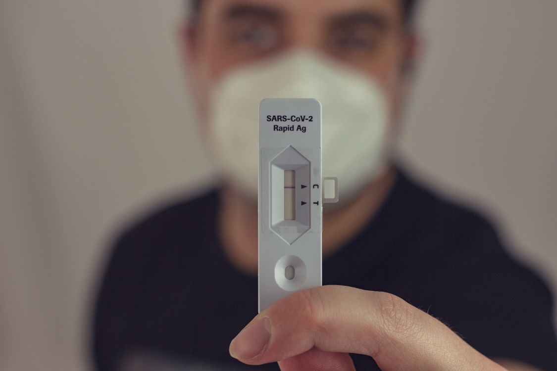 Free A person holding a negative COVID-19 antigen test with a face mask on, focused on the test result. Stock Photo