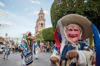 热闹的街头节日上，参加者们戴着传统面具、穿着传统服装，庆祝文化游行