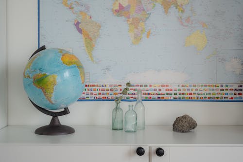 Globe, Clear Bottles and Rock on White Surface