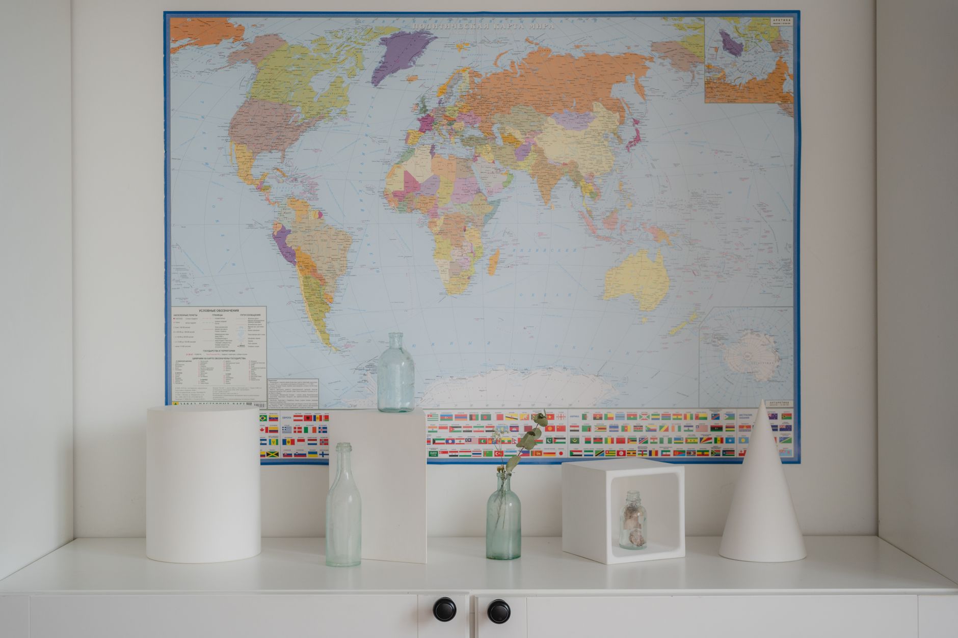 A minimalist interior design featuring glass bottles and a colorful world map.
