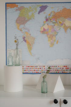 Minimalist composition with glass vases and a world map, evoking travel themes.