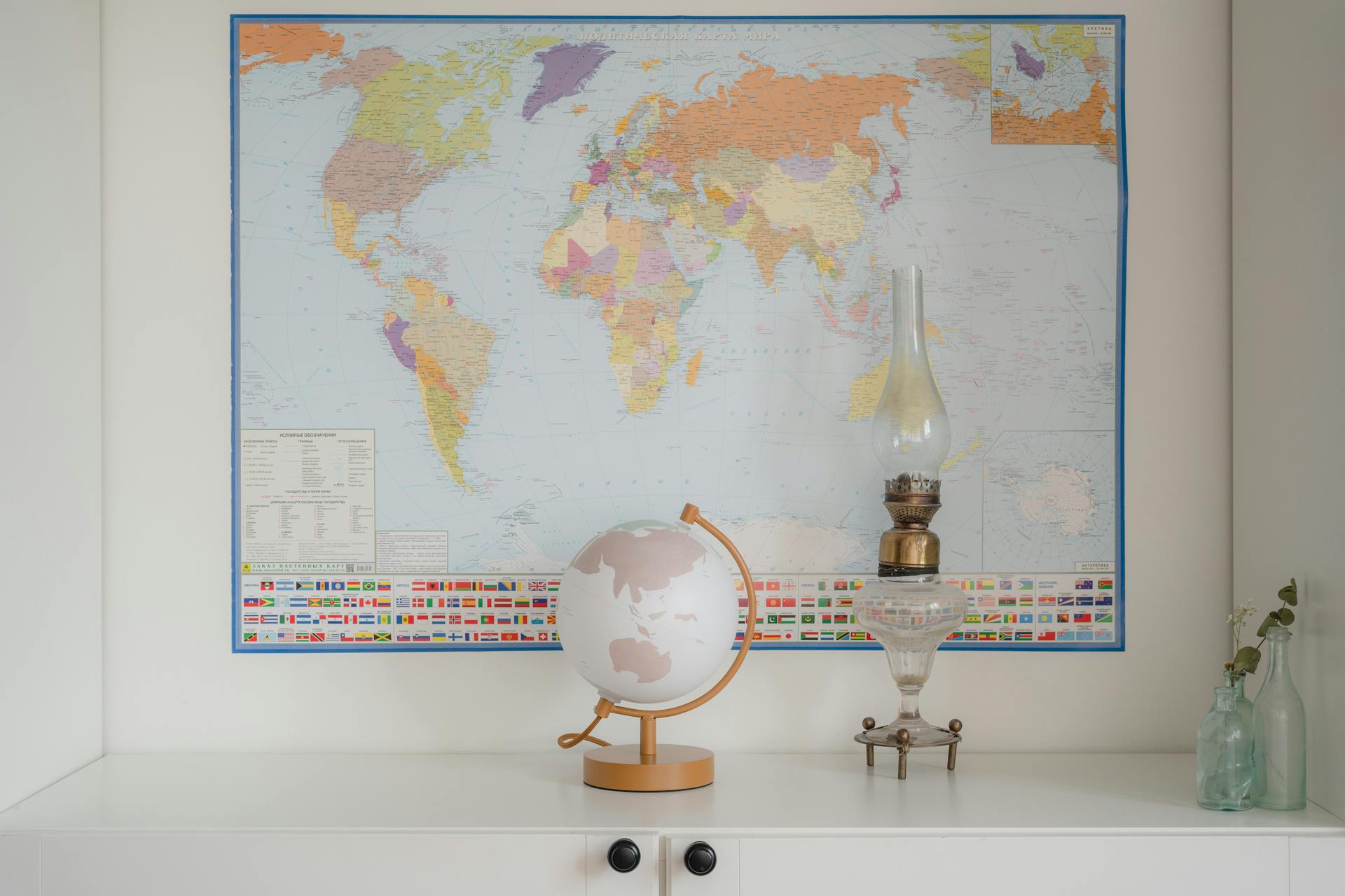 A world map displayed with a globe and vintage lamp on a shelf.