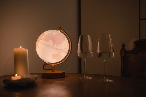 Free Warm indoor ambiance with a glowing globe, candlelight, and wine glasses on a wooden table. Stock Photo