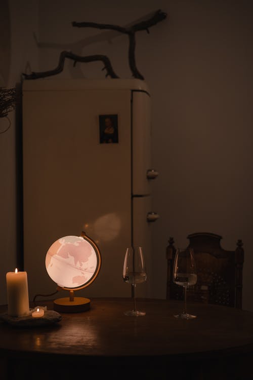 An Illuminated Globe beside Wine Glasses