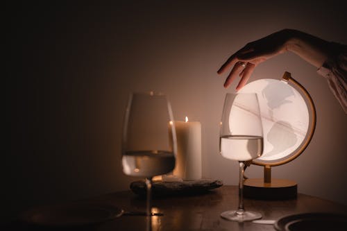 A Person Touching an Illuminated Globe beside Wine Glasses