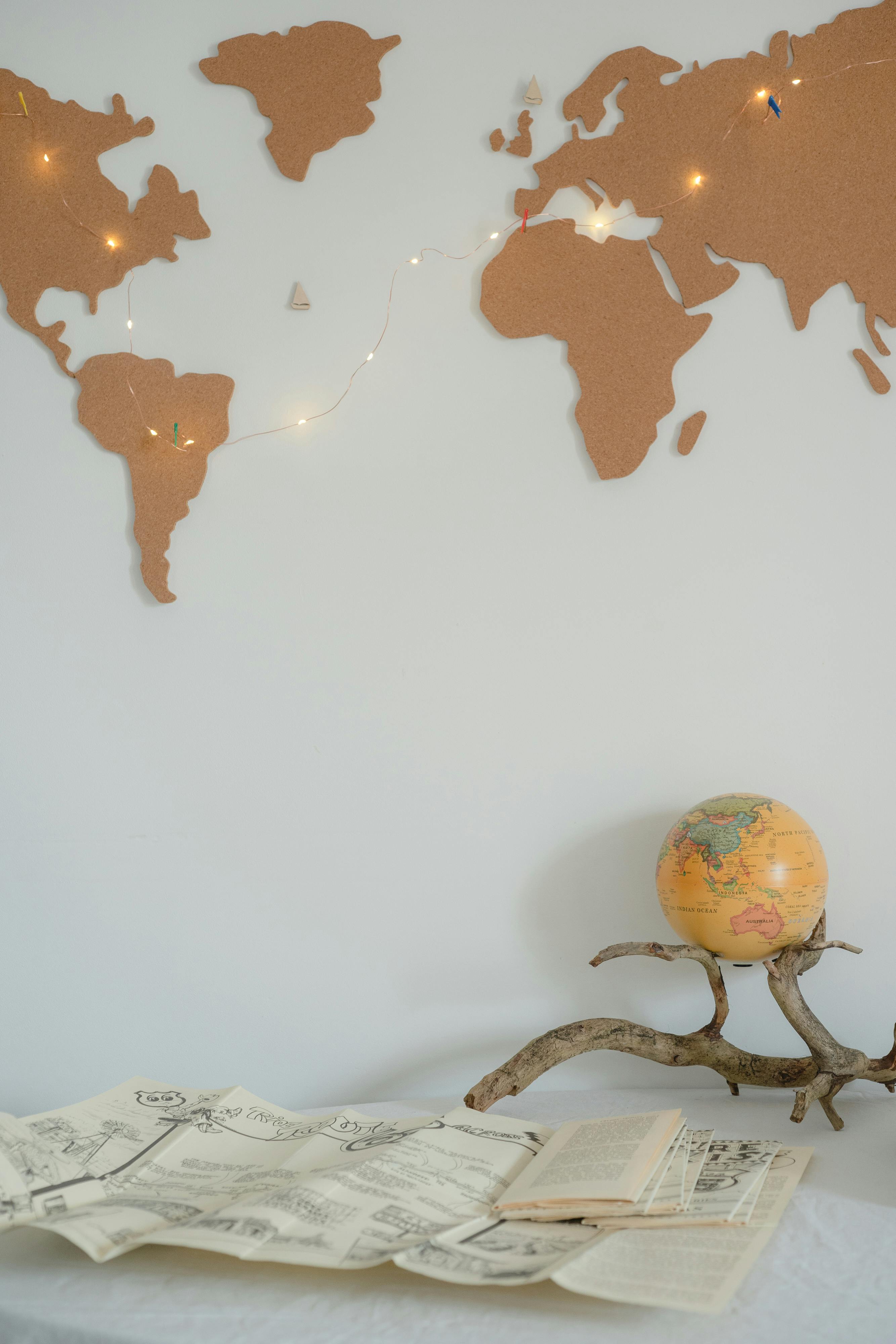 Free A cozy study setup featuring a globe and fairy lights against a map-themed white wall. Stock Photo