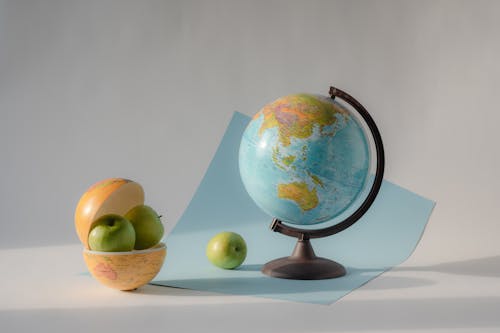 Green Apple Near a Globe on Blue Paper