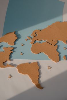 Stylized cork world map on blue paper with shadows, highlighting continents. 7634559