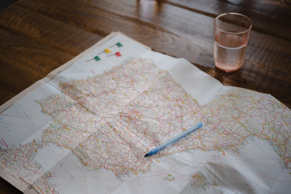 Map highlighting Spain and Portugal with a pen and glass on a wooden table.