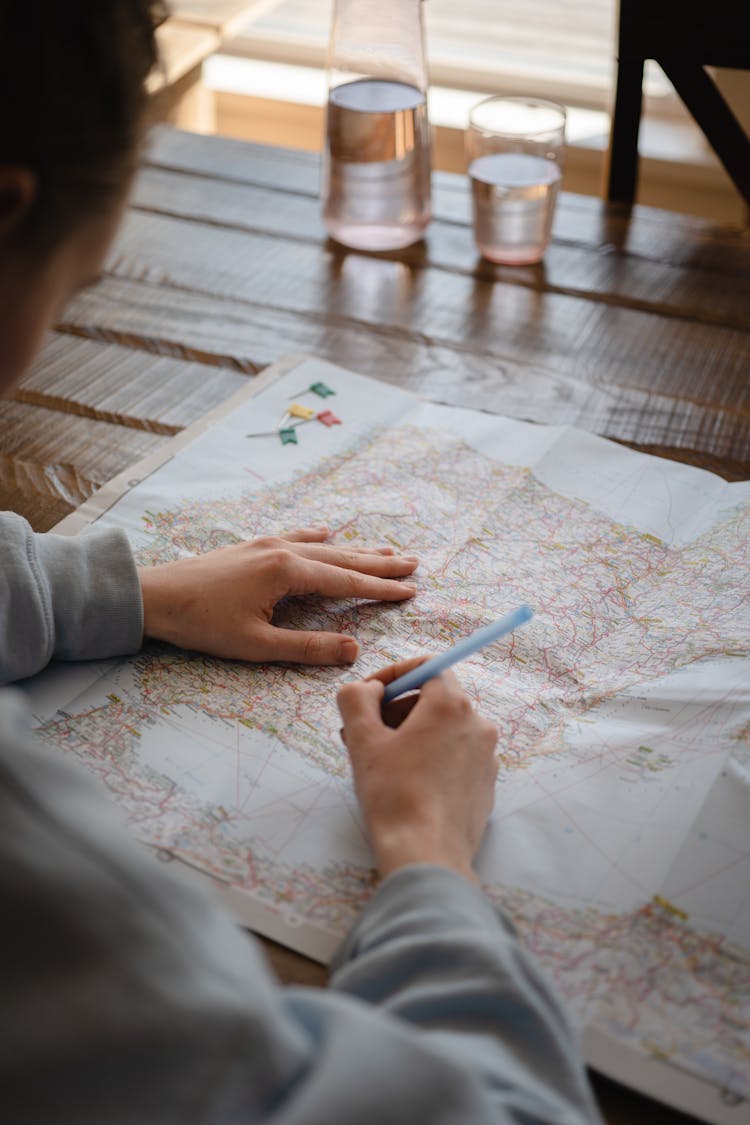 A Person Writing On A Paper Map