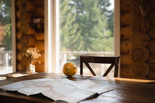 Paper Map and Globe on Wooden Table