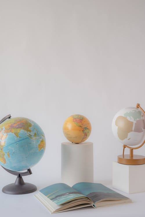 Globes on the White Table Near a Book