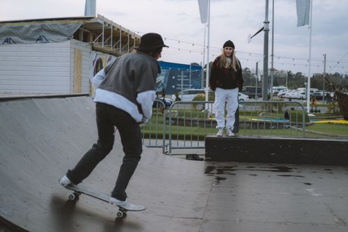 Free Two skateboarders, a man and woman, practicing on an outdoor ramp during the day. Stock Photo