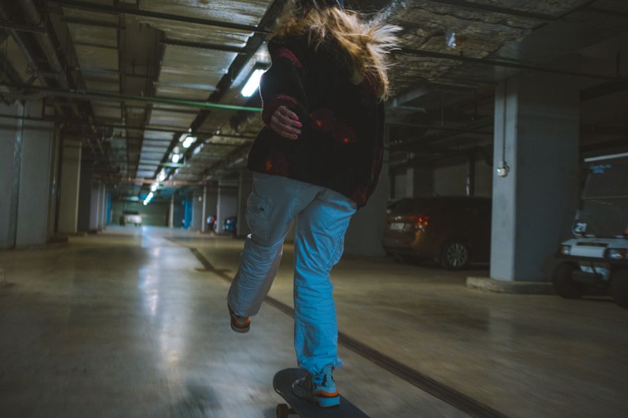 Skater riding through a dim parking garage, photo by Yaroslav Shuraev on Pexels