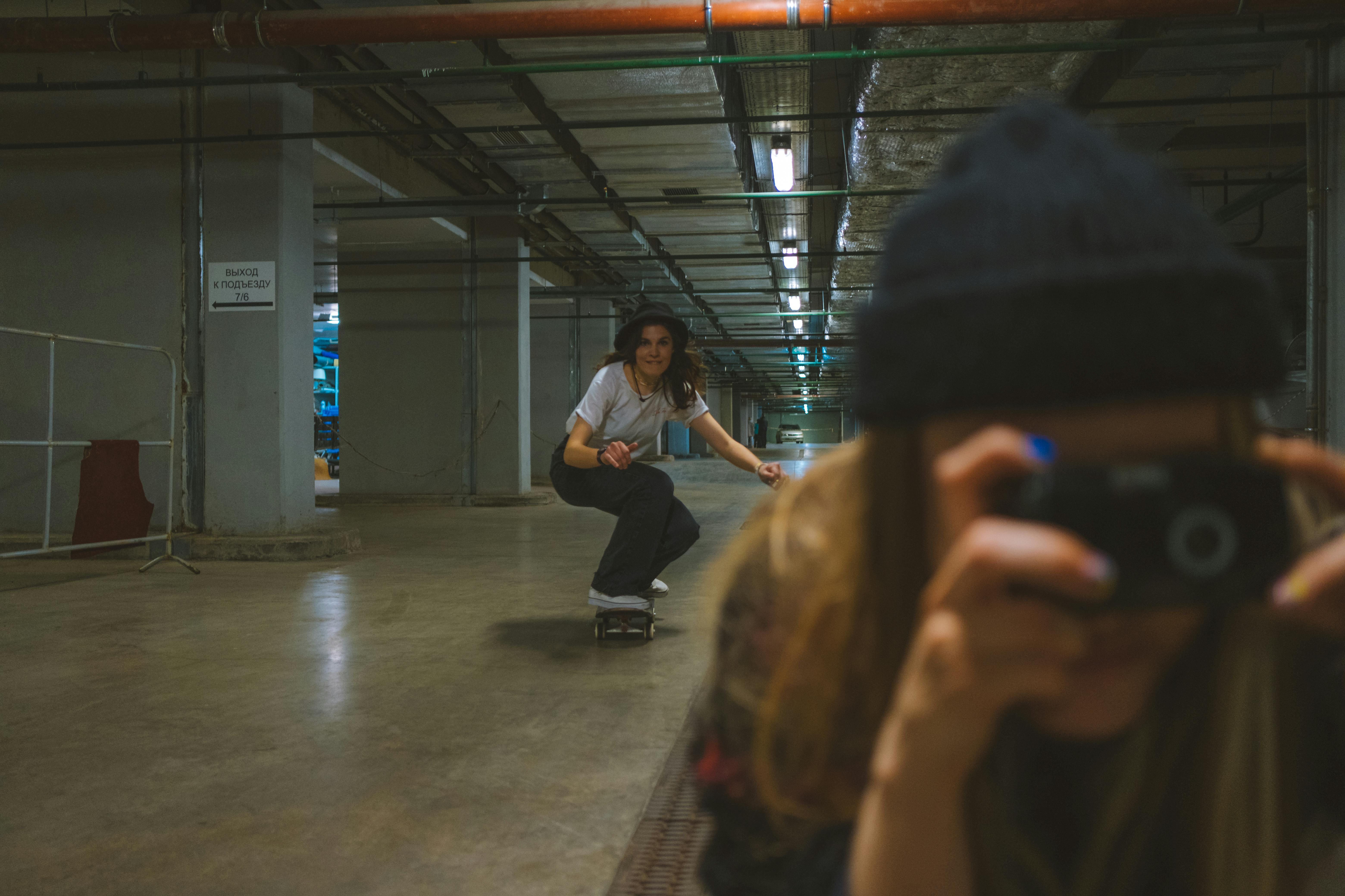 a woman riding a skateboard behind a person using the camera