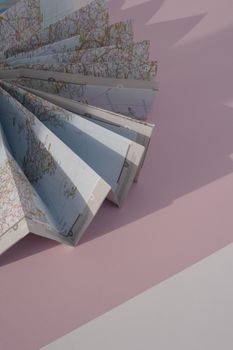 A folded world map lying on a pastel pink background, ideal for travel themes.